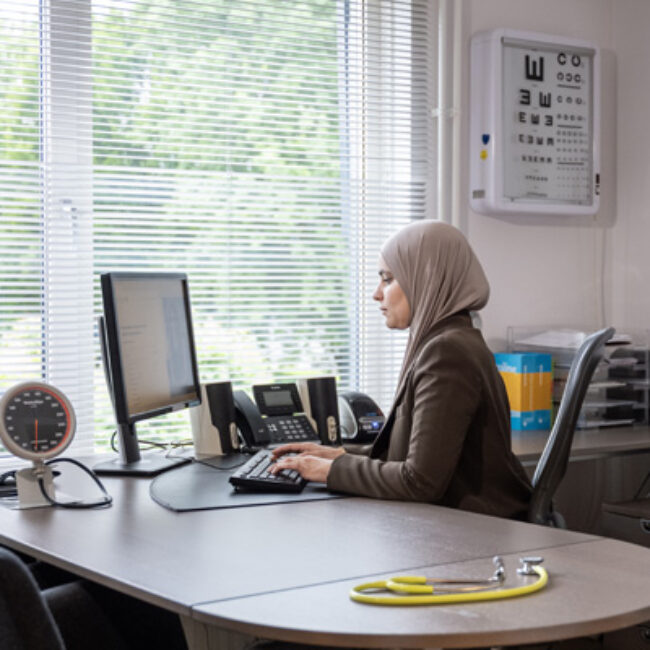 Doktersassistent werkt achter computer